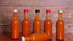 six bottles filled with hot sauce sitting on top of a wooden table