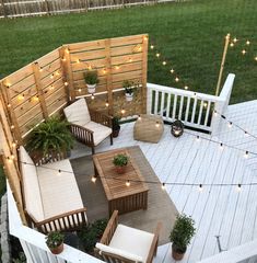 an outdoor patio with wooden furniture and string lights on the deck, surrounded by grass