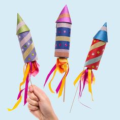 hand holding three colorful party hats with streamers attached to the top and one being held up by two fingers