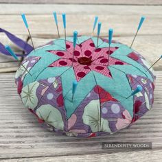 a pin cushion with pins stuck in it on a wooden table next to a pair of scissors