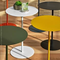 three round tables with different colored tops and one has a plant in the vase on top