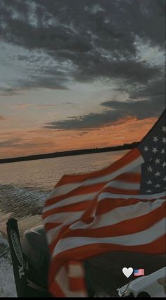 an american flag is waving in the wind on a boat at sunset or dawn,