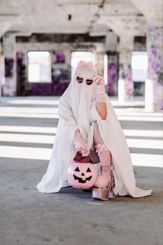 a woman dressed as a nun holding a jack - o - lantern and wearing pink shoes