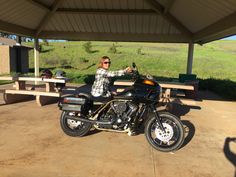 a man riding on the back of a black motorcycle next to a picnic table and bench