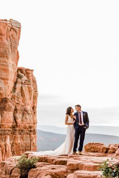 a bride and groom standing on the edge of a cliff at their wedding ceremony in colorado