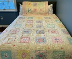 a bed with a quilt on top of it in a room next to a window