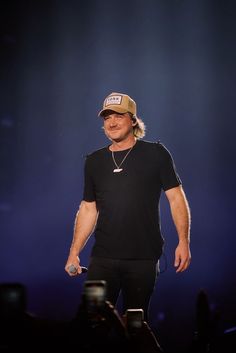 a man in black shirt and hat standing on stage