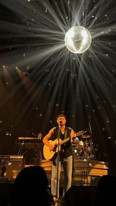 a man standing on top of a stage holding a guitar