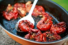 tomatoes being cooked in a skillet with a spoon