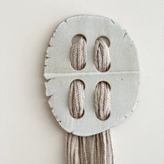 a white wall hanging with three buttons and two strings attached to the back of it