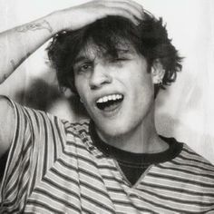 a black and white photo of a young man holding his hair in front of his head