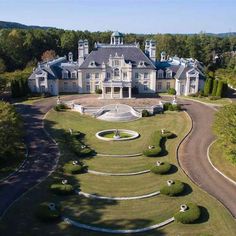 an aerial view of a large mansion in the middle of a lush green field with trees