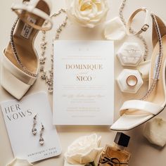 the wedding stationery is laid out with shoes and jewelry