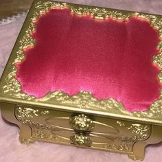 a pink and gold box sitting on top of a white blanket