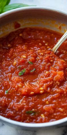 a bowl of tomato sauce with a spoon in it