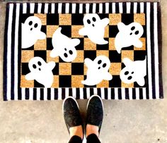 a person standing next to a black and white checkered rug with ghost faces on it