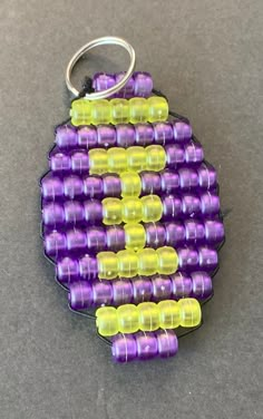 a purple and yellow beaded keychain sitting on top of a gray surface