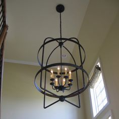 a chandelier hanging from the ceiling in a room with two windows and a window