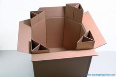 an open cardboard box sitting on top of a white table with the bottom half cut out