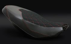 a close up of a motorcycle seat on a black background with red stitching around it