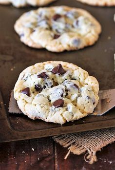 chocolate chip cookies on a cookie sheet with a spatula in the foreground and another cookie behind it