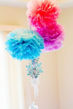 two tissue pom poms hanging from a chandelier with snowflakes