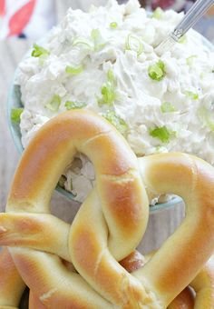 two pretzels in the shape of hearts on a plate next to a bowl of whipped cream