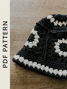 a black and white crocheted hat sitting on top of a wooden table