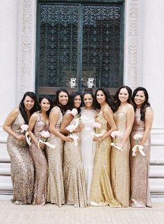 a group of women standing next to each other in front of a door wearing dresses