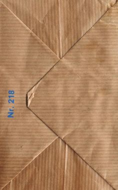 an origami piece with blue numbers on it and some brown paper in the background