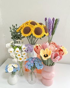 several vases filled with different types of flowers on a white counter top next to each other