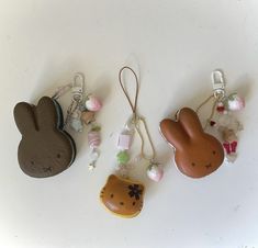 three different shaped key chains with charms attached to them on a white surface next to each other