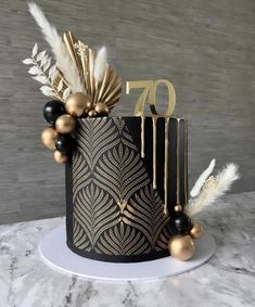 a black and gold birthday cake with feathers on top