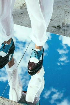 a person wearing white pants and blue shoes standing on a skateboard with their feet in the air