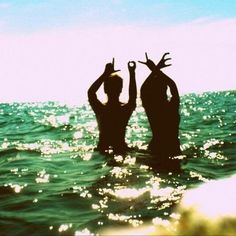 two people standing in the water with their hands up