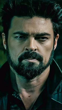 a man with black hair and beard wearing a leather jacket