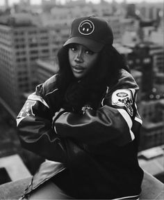 a black and white photo of a person wearing a hat on top of a building