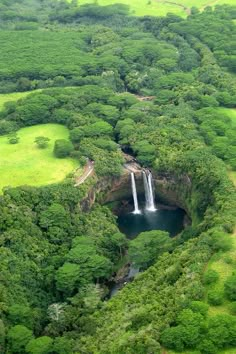 an aerial view of a waterfall surrounded by lush green trees