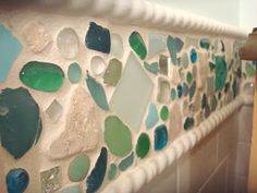 a close up of a bathroom wall with many different colored glass pieces on the walls