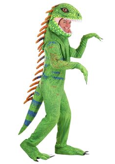 a man in a green dinosaur costume is holding his hand out to the side while standing