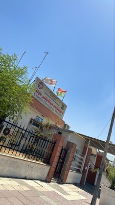 a clock tower on the side of a building with flags flying in the air above it