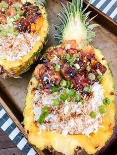 two pineapple halves with rice and meat on them