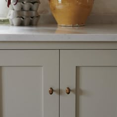 two yellow vases sitting on top of a white countertop next to each other