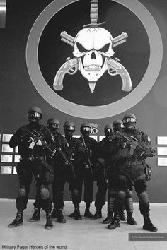 a group of soldiers standing next to each other in front of a wall with a skull on it