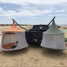 two tents set up on the beach next to a pickup truck with an awning