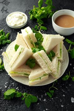 several sandwiches on a plate with dipping sauces and green leafy garnish