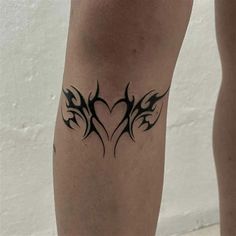 a tattoo on the leg of a person with black ink and an arrow in the shape of a heart