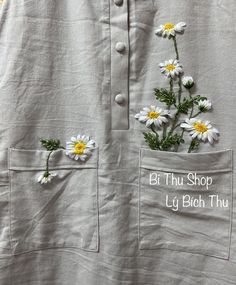 white daisies are in the pocket of a gray shirt with words written on it