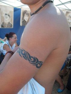 a man with a tattoo on his arm at an outdoor event in front of other people