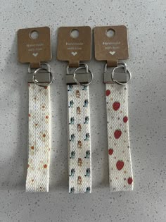 three lanyards with hearts on them are hanging from the side of a counter